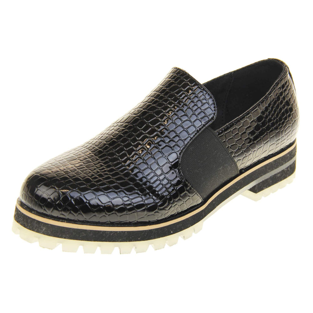 Croc loafers womens. Loafer style shoes with a black faux snakeskin upper. With twin black elasticated side panels. Chunky black and cream sole with slip resistant grip to the bottom. Left foot at an angle.