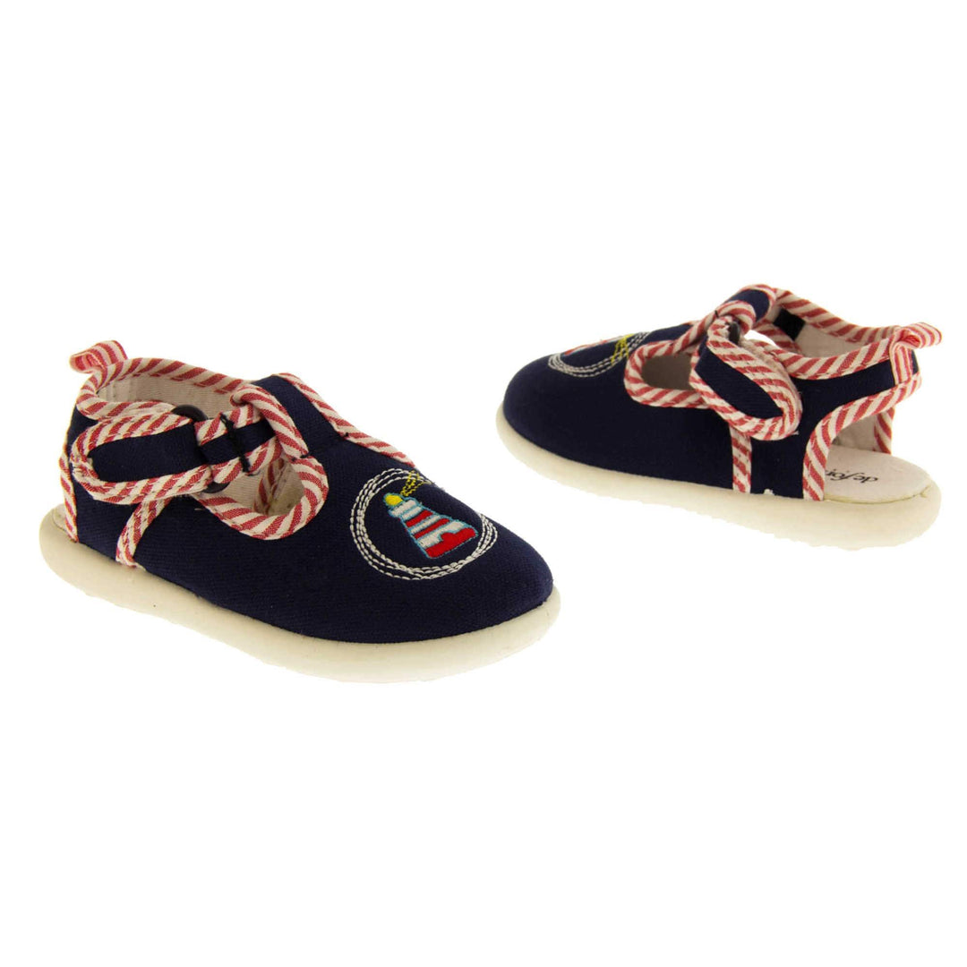 Boys sandals. Navy canvas sandals with cut out heel. White sole with lighthouse detail on the front of the shoes and red and white striped edging. Both shoes facing top and tail.