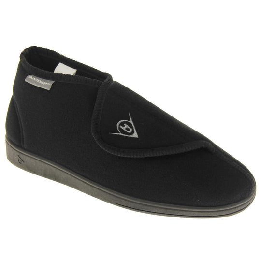 Orthopaedic slipper boots. Mens orthopaedic slippers in an ankle boot style. With a soft black textile upper and black textile lining. With an adjustable touch close top with a grey Dunlop logo on. Small grey label to the outer side edge with Dunlop written on. Thick black outdoor sole. Right foot at an angle.