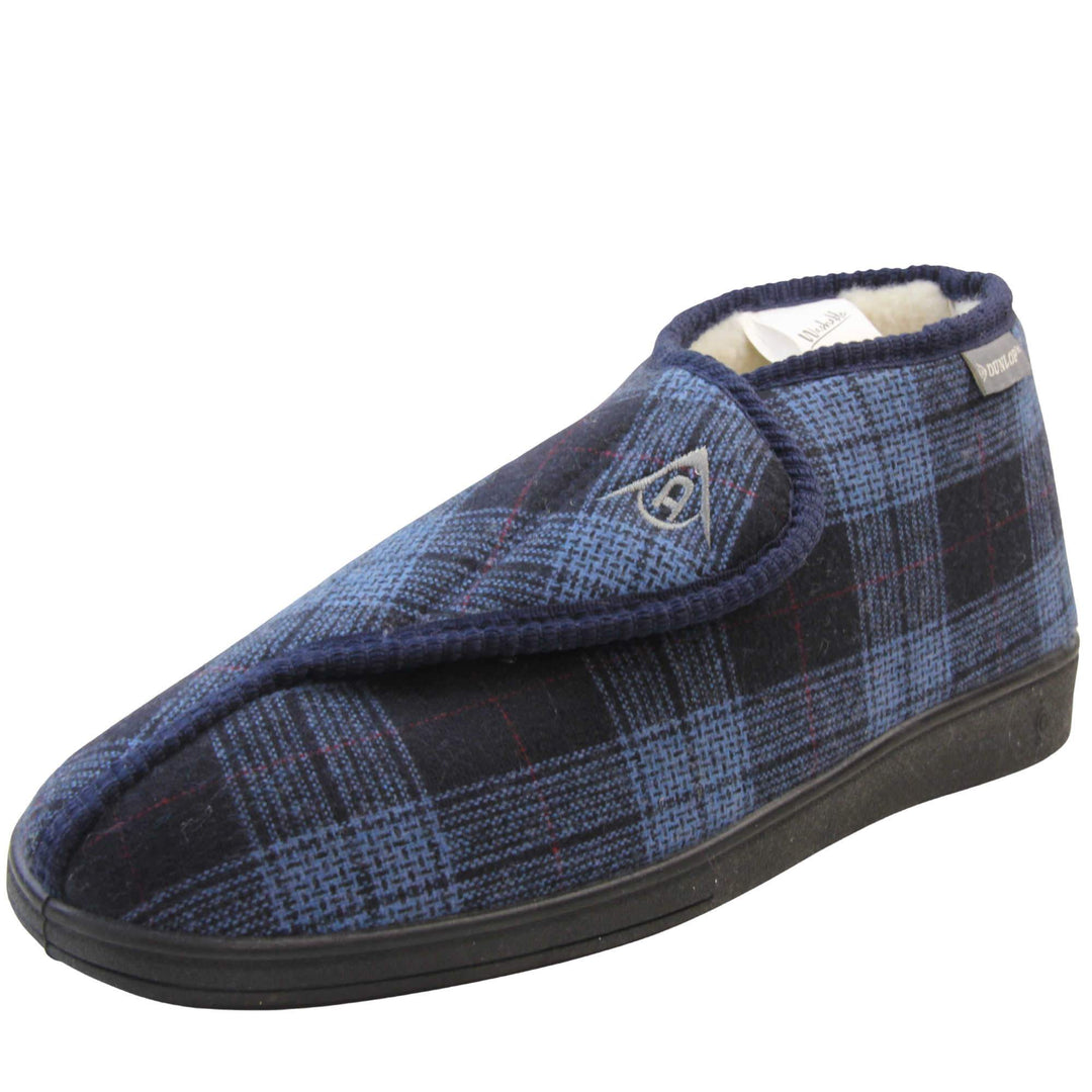 Orthopaedic boot slippers. Mens orthopaedic slippers in an ankle boot style. With a navy blue plaid upper and white fleece lining. With an adjustable touch close top with a grey Dunlop logo on. Small grey label to the outer side edge with Dunlop written on. Thick black outdoor sole. Left foot at an angle.
