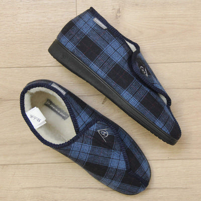 Orthopaedic boot slippers. Mens orthopaedic slippers in an ankle boot style. With a navy blue plaid upper and white fleece lining. With an adjustable touch close top with a grey Dunlop logo on. Small grey label to the outer side edge with Dunlop written on. Thick black outdoor sole. Lifestyle photo with both shoes with right foot on its side, on a wood floor, taken from above