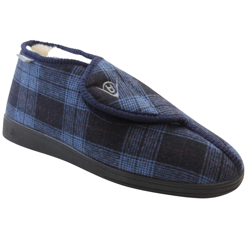 Orthopaedic boot slippers. Mens orthopaedic slippers in an ankle boot style. With a navy blue plaid upper and white fleece lining. With an adjustable touch close top with a grey Dunlop logo on. Small grey label to the outer side edge with Dunlop written on. Thick black outdoor sole. Right foot at an angle.
