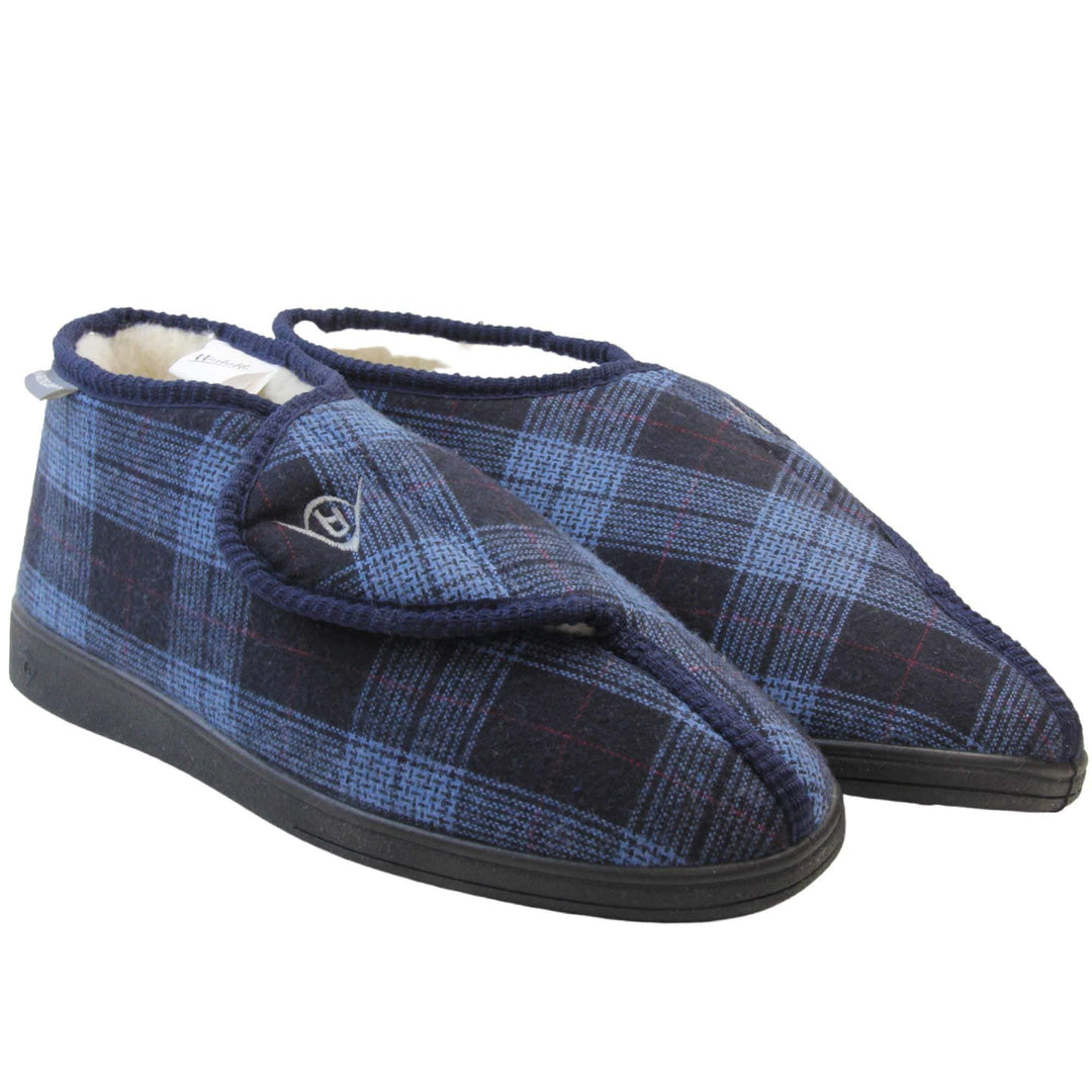 Orthopaedic boot slippers. Mens orthopaedic slippers in an ankle boot style. With a navy blue plaid upper and white fleece lining. With an adjustable touch close top with a grey Dunlop logo on. Small grey label to the outer side edge with Dunlop written on. Thick black outdoor sole. Both feet together at an angle