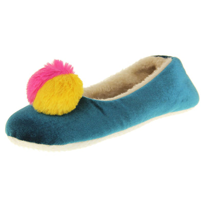 Womens ballet slippers. Ladies slippers in a ballerina style. Teal velvety upper with fluffy yellow and pink pom pom on the top. Cream faux fur lining. Beige textile sole with bumps to the bottom for grip. Left foot at an angle.