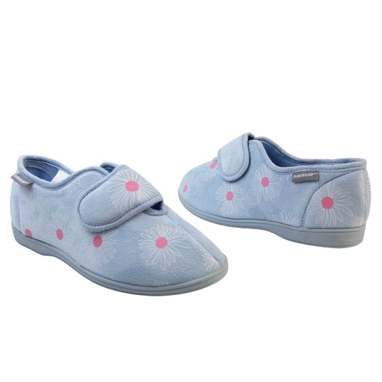 Slippers for swollen feet. Womens full back slipper. With a pale blue upper with white daisy design with bright pink for the middle of the flowers. Touch fasten strap over the top of the foot to adjust the fit. Matching blue textile lining and sole. Both feet at an angle, facing top to tail.