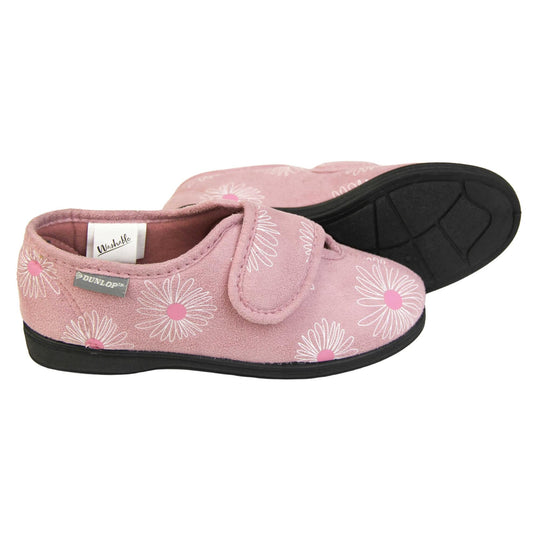 Adjustable slippers womens. Ladies full back slipper. Pale pink upper with white daisy design and bright pink for the middle of the flowers. Touch fasten strap over the top of the foot to adjust the fit. Matching pink textile lining and firm black sole. Both feet from a side profile with the left foot on its side behind the the right foot to show the sole.