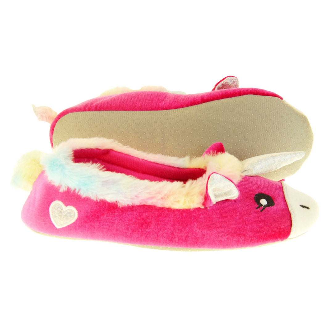 Unicorn slippers womens. Ladies slippers in a ballerina style. With bright pink velvety upper, cute embroidered horse face,shiny horn and rainbow faux fur collar. Warm pink lining. Beige textile sole with bumps to the bottom for grip. Both feet from a side profile with the left foot on its side to show the sole.
