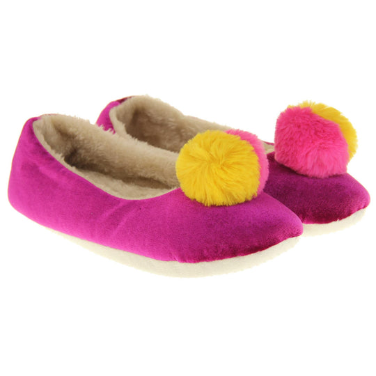 Womens ballet slippers. Ladies slippers in a ballerina style. Fuchsia velvety upper with fluffy yellow and pink pom pom on the top. Cream faux fur lining. Beige textile sole with bumps to the bottom for grip. Both feet together at an angle.