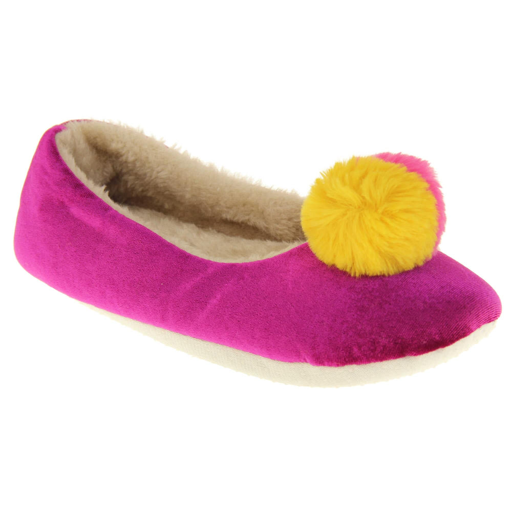 Womens ballet slippers. Ladies slippers in a ballerina style. Fuchsia velvety upper with fluffy yellow and pink pom pom on the top. Cream faux fur lining. Beige textile sole with bumps to the bottom for grip. Right foot at an angle.