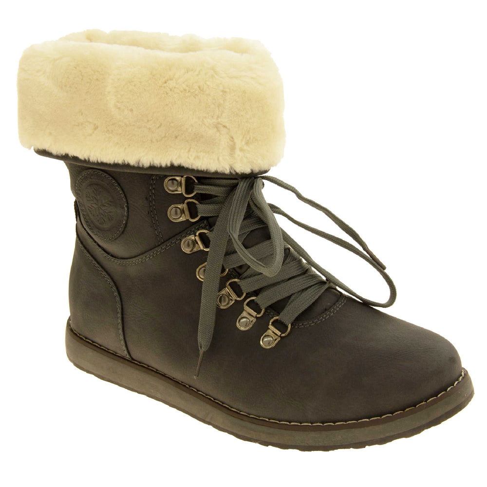 Faux fur lined winter boot. Women's boot in an ankle style with a grey faux suede upper. Pull on design with grey faux laces detail to the front. Cream faux fur lining and collar. Grey sole with grip to the bottom. Right foot at an angle.