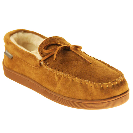 Faux fur moccasins. Closed back slippers in a moccasin style with tan brown suede leather upper and bow. Cream faux fur lining. Thick brown sole. Right foot at an angle.