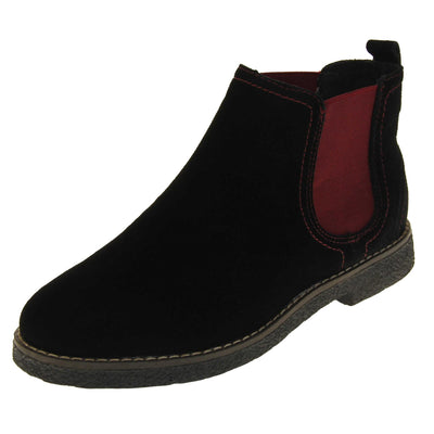 Flat suede ankle boots women's. Chelsea boot style with a black suede upper. Burgundy elasticated panels at the ankles and a black loop at the heel to help pull them on. Black coloured sole with a very slight heel. Left foot at an angle.