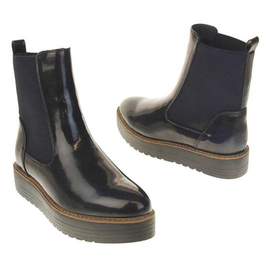 Fleece lined boots women's. Faux leather, tall Chelsea boot style with a black upper. Black elasticated panels at the ankles and a black loop at the heel to help pull them on. Black coloured low platform sole. Both feet from a slight angle facing top to tail.