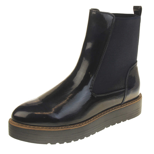 Fleece lined boots women's. Faux leather, tall Chelsea boot style with a black upper. Black elasticated panels at the ankles and a black loop at the heel to help pull them on. Black coloured low platform sole. Left foot at an angle