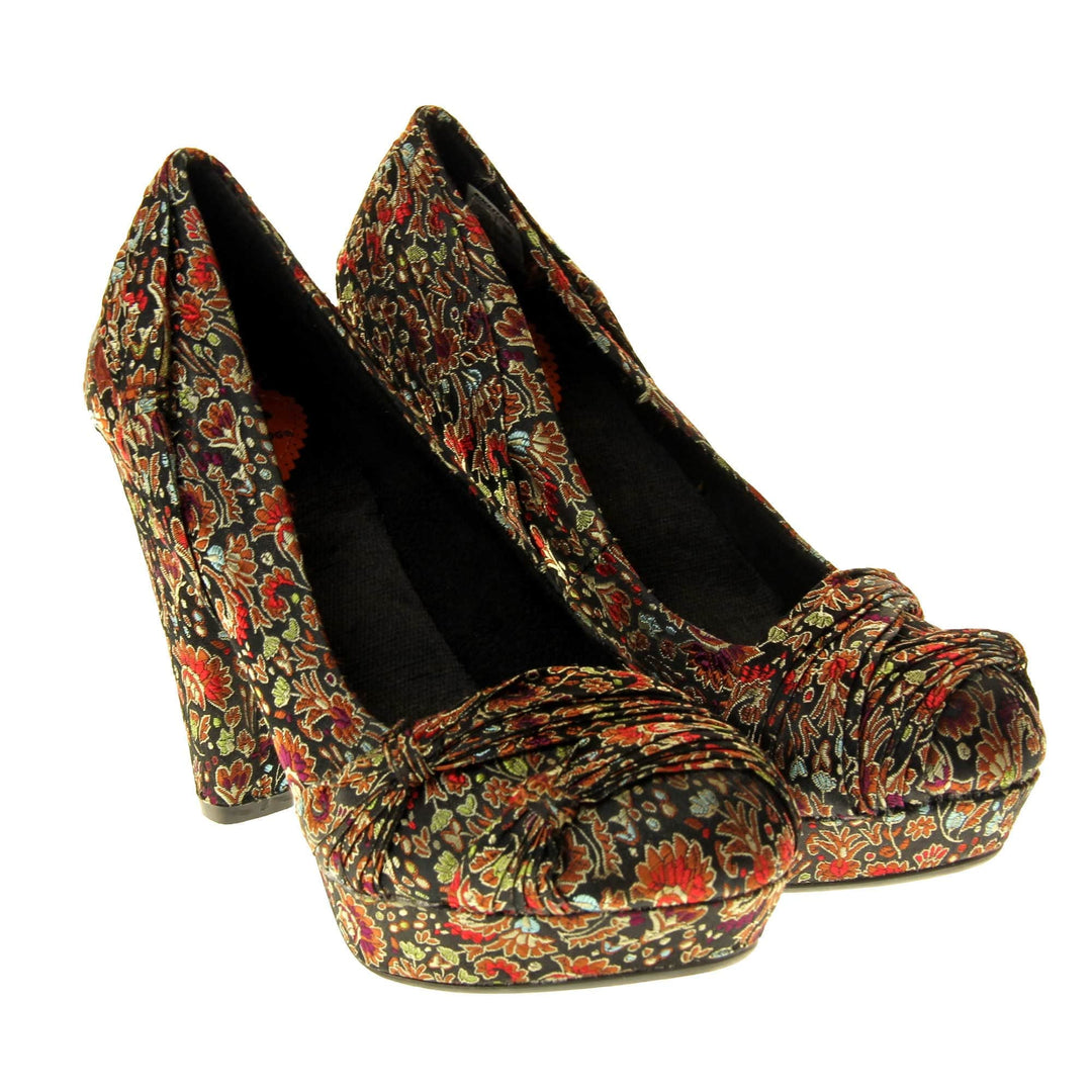 Floral block heels. Womens high heels with a floral textile upper. Ruched detailing to the front. Black textile lining with a red circle on the insole with black Rocket Dog logo. Small platform on the front of the outsole with a chunky block heel to the back covered in the same textile as the upper. Black sole to the bottom. Both feet together at a slight angle.