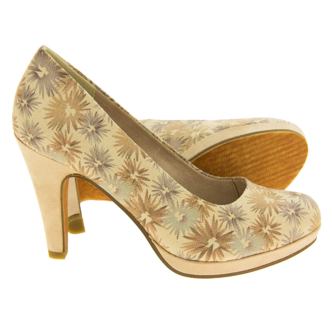 Floral heels. Womens court shoes with a cream upper with faded floral multi coloured pattern. Matching insole with Marco Tozzi branding. Taupe faux suede lining. Small cream platform and mid stiletto heel. Brown sole. Both feet from a side profile with the left foot on its side behind the the right foot to show the sole.