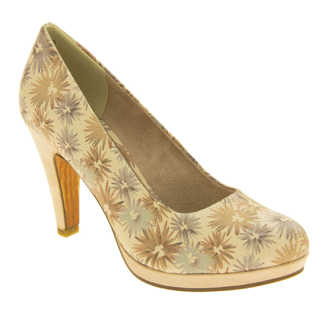 Floral heels. Womens court shoes with a cream upper with faded floral multi coloured pattern. Matching insole with Marco Tozzi branding. Taupe faux suede lining. Small cream platform and mid stiletto heel. Brown sole. Right foot at an angle.