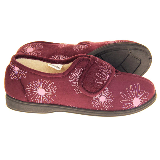 Floral slippers. Womens full back slipper. Burgundy upper with white daisy design and bright pink for the middle of the flowers. Touch fasten strap over the top of the foot to adjust the fit. Cream fleece lining and firm black sole. Both feet from a side profile with the left foot on its side behind the the right foot to show the sole.