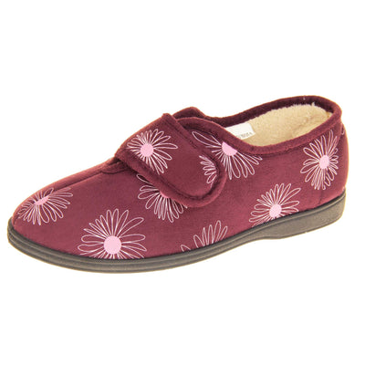 Floral slippers. Womens full back slipper. Burgundy upper with white daisy design and bright pink for the middle of the flowers. Touch fasten strap over the top of the foot to adjust the fit. Cream fleece lining and firm black sole. Left foot at an angle.