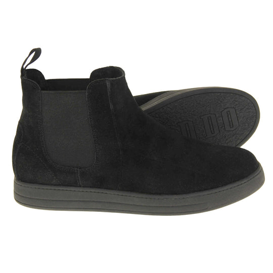 Fur lined ankle boots women's. Chelsea style boot with a black suede upper. Black elasticated panels at the ankles and black faux fur lining. A loop at the heel to help pull them on. Black outsole. Both feet from a side profile with the left foot on its side to show the sole.
