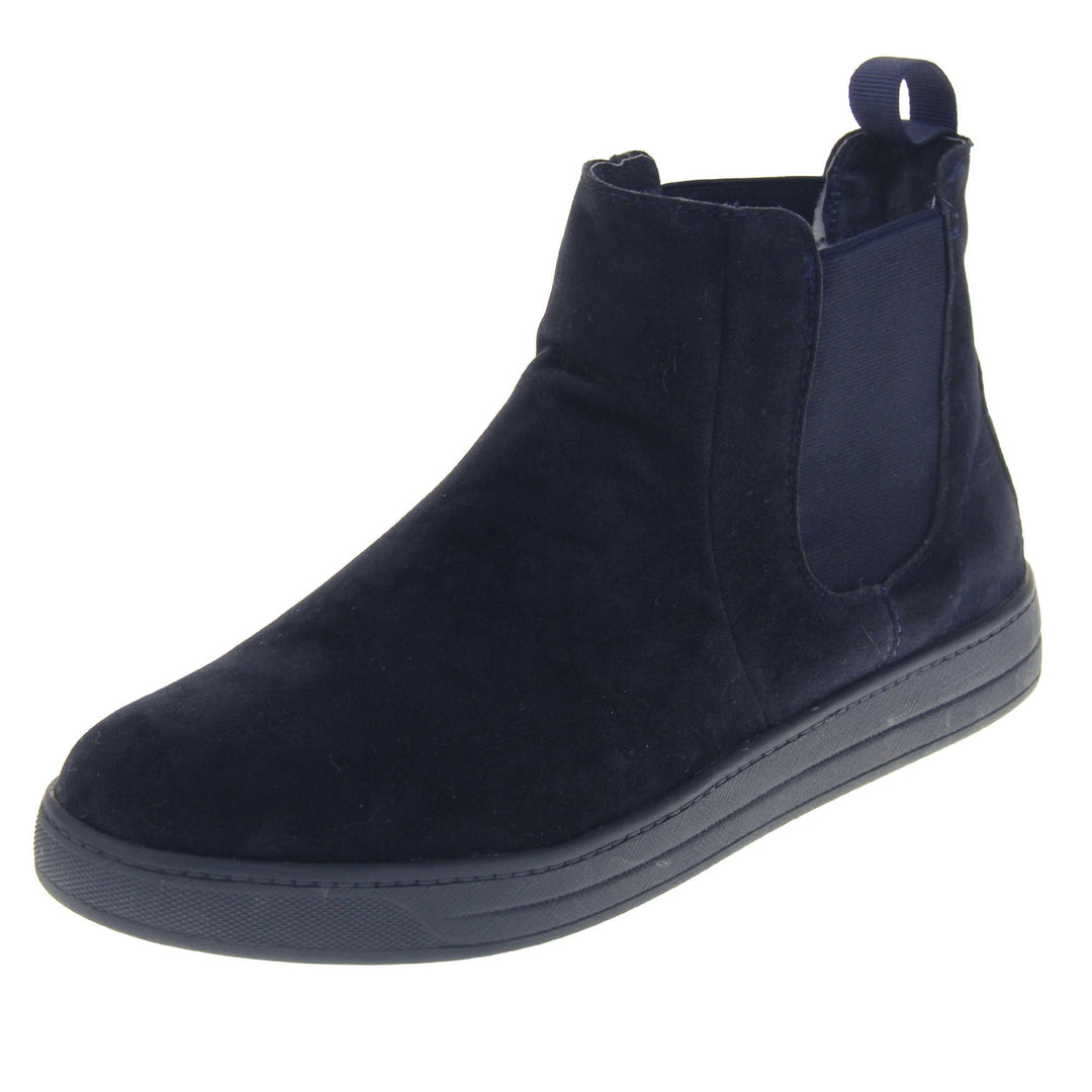 Fur lined Chelsea boots. Women's ankle boot with a navy blue suede upper. Navy elasticated panels at the ankles and navy faux fur lining. A navy loop at the heel to help pull them on. Black outsole. Left foot at an angle.