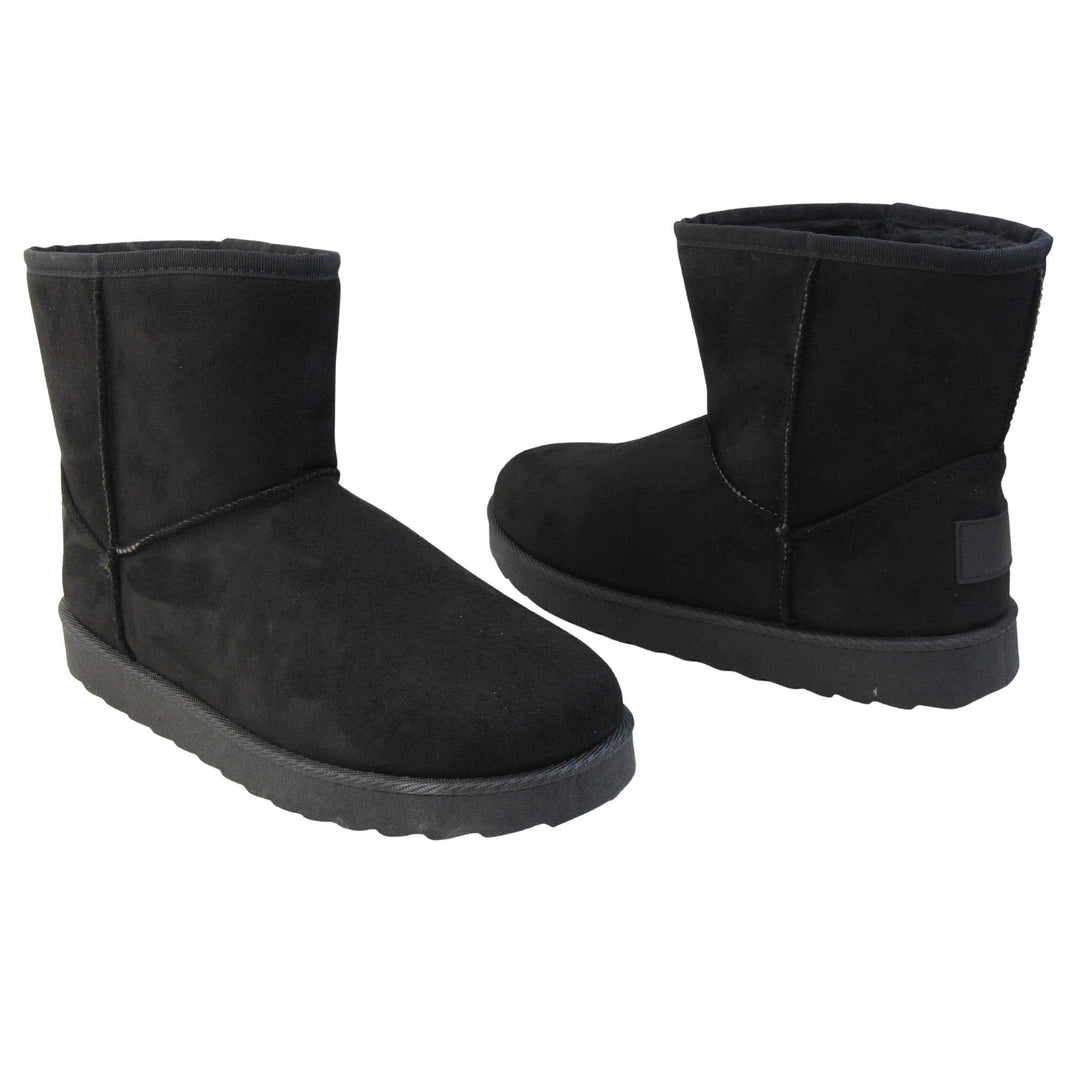 Fur lined winter boots. Ankle boots with a black faux suede upper and stitching detail. Black faux fur lining. Chunky black sole with deep tread to the bottom. Both feet from a slight angle facing top to tail.
