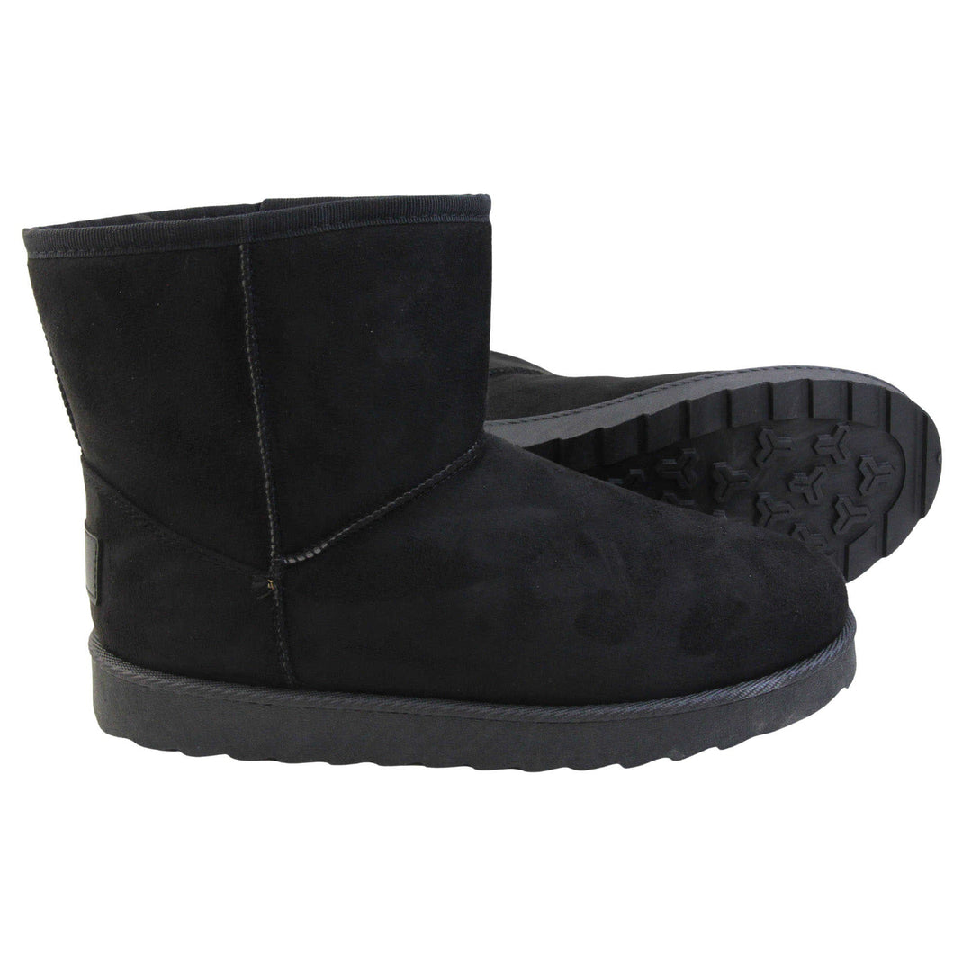 Fur lined winter boots. Ankle boots with a black faux suede upper and stitching detail. Black faux fur lining. Chunky black sole with deep tread to the bottom. Both feet from a side profile with the left foot on its side to show the sole.