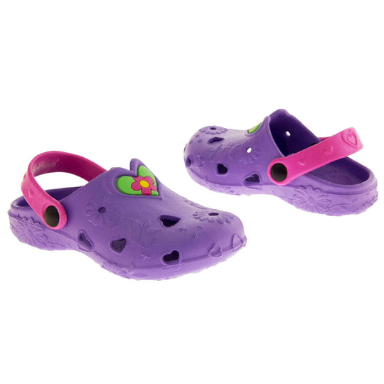 Girls Beach Shoes. Purple synthetic clog style shoes with embossed flowers and stars. Cut out love hearts and centre of flowers on the upper. Green love heart, with pink and yellow flower in the centre, to the middle top of the upper. Pink strap that goes along the back of your heel. The strap can be moved along the top of the shoe instead to make the shoe a mule.  Both shoes at a slight angle facing top to tail.