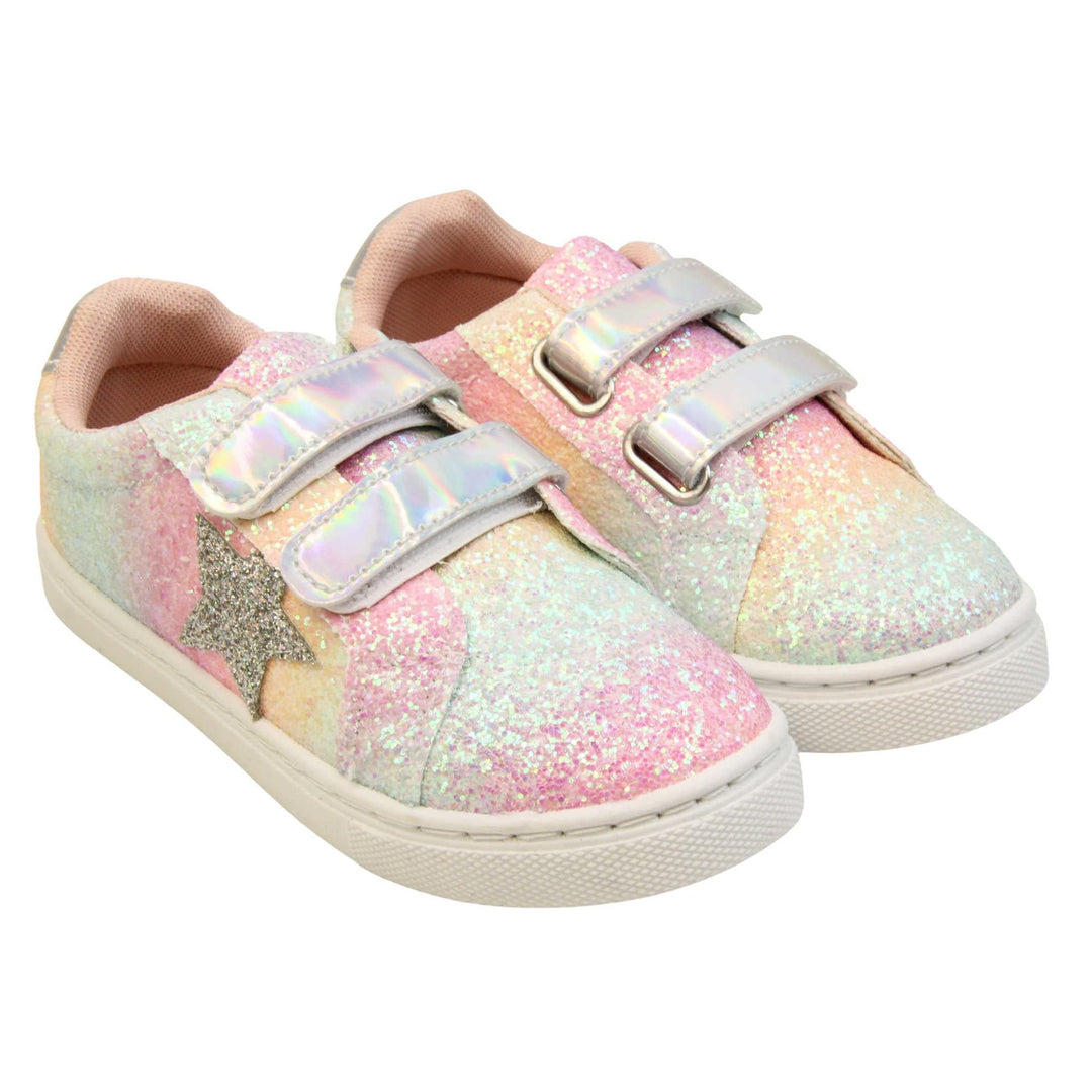 Girls glitter trainers. Kids trainers with a ombre rainbow upper done in glitter. With two silver holographic touch fasten straps. A silver glitter heart detail to the outside of the shoe in the middle of the foot. Pale pink textile lining and chunky white sole. Both feet together at an angle.
