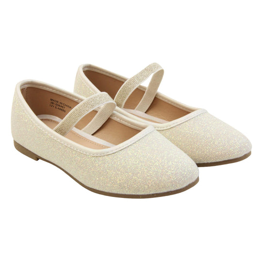Girls party shoes. Ballerina style shoes with ivory glitter uppers. With a gold glitter elasticated over the foot strap. Cream faux leather collar and beige lining. Dark brown sole with very slight heel. Both feet together at an angle.