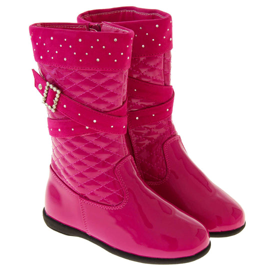Girls pink boots. Fuchsia patent leather effect uppers with ankle upwards being a quilted style. With faux suede cuff and straps that both have diamantes on. Diamante buckle on the straps. Zip fastening to the inside leg. Black synthetic sole. Both boots together at an angle.