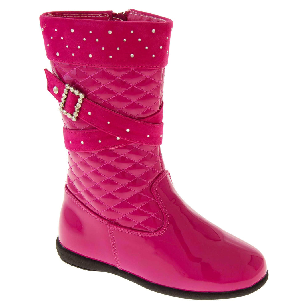 Girls pink boots. Fuchsia patent leather effect uppers with ankle upwards being a quilted style. With faux suede cuff and straps that both have diamantes on. Diamante buckle on the straps. Zip fastening to the inside leg. Black synthetic sole. Right foot at an angle.