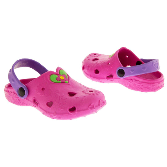 Girls Sandals. Pink synthetic clog style shoes with embossed flowers and stars. Cut out love hearts on the upper. Green love heart, with pink and yellow flower in the centre, to the middle top of the upper. Purple strap that goes along the back of your heel. The strap can be moved along the top of the shoe instead to make the shoe a mule. Both shoes at a slight angle facing top to tail.