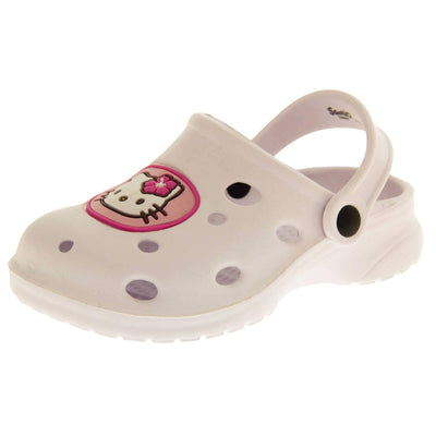 Girls Sandals White. White synthetic clog sandals with holes in the upper. Hello Kitty face in a pink circle to the front. White strap with black studs to attach to the back of the shoe. The strap can be worn around the back of the heel or over the top of the shoe in a mule. White sole with slight heel to the back. Left foot at an angle.
