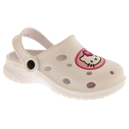 Girls Sandals White. White synthetic clog sandals with holes in the upper. Hello Kitty face in a pink circle to the front. White strap with black studs to attach to the back of the shoe. The strap can be worn around the back of the heel or over the top of the shoe in a mule. White sole with slight heel to the back. Right foot at an angle.