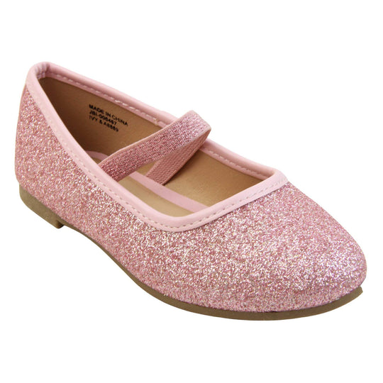 Girls sparkly shoes. Ballerina style shoes with pink glitter uppers. With a pink glitter elasticated over the foot strap. Pink faux leather collar and beige lining. Dark brown sole with very slight heel. Right foot at an angle.