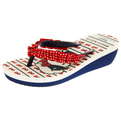 Girls wedge sandals. Hello Kitty flip flop sandal. White top with Hello Kitty design. Blue synthetic between toe strap with red textile frill with white spots. Small wedge heel. Blue sole. Left foot at an angle