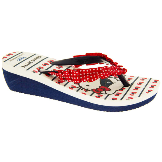 Girls wedge sandals. Hello Kitty flip flop sandal. White top with Hello Kitty design. Blue synthetic between toe strap with red textile frill with white spots. Small wedge heel. Blue sole. Right foot at an angle