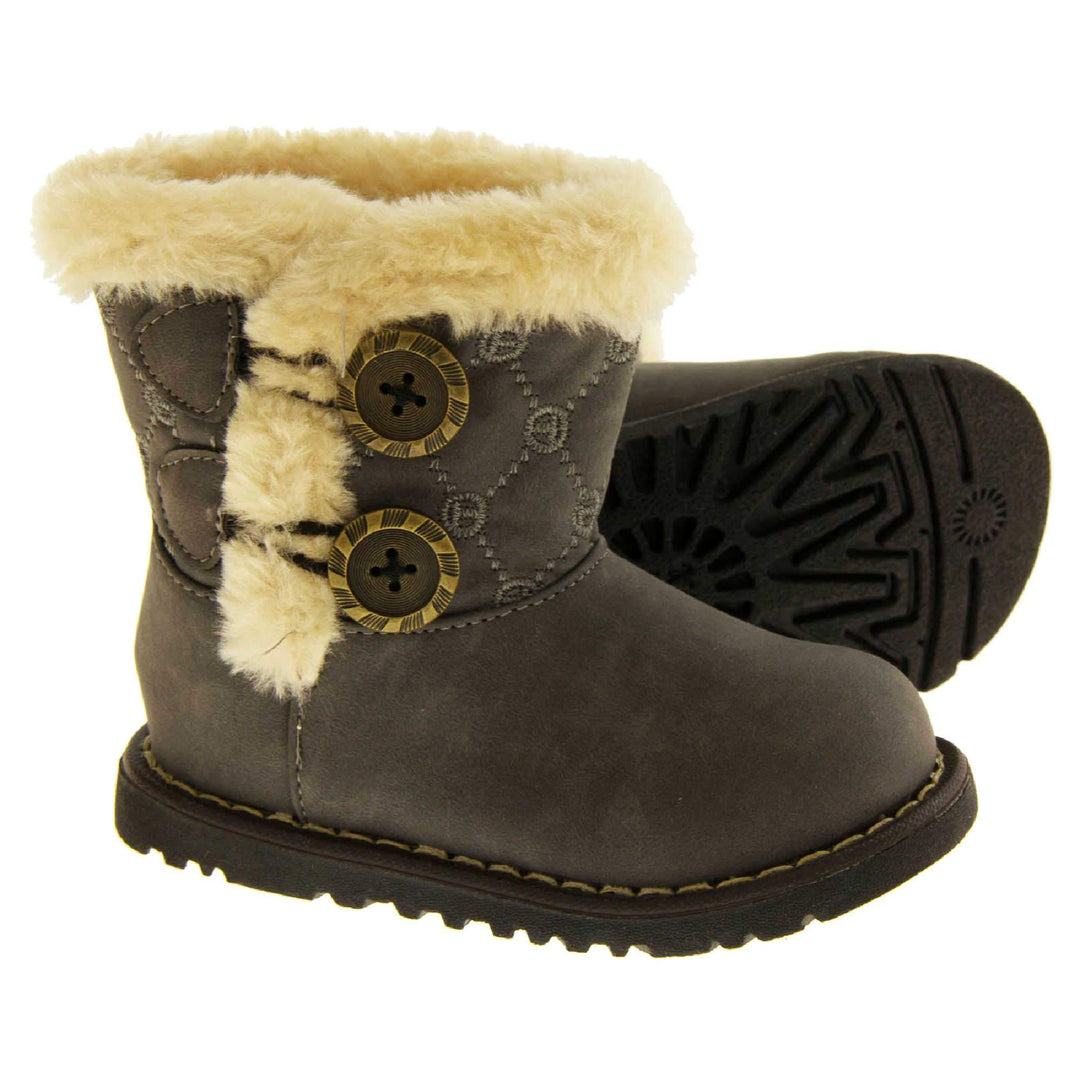 Girls Winter Boot Infant Sizes. Grey faux suede with chunky black sole and cream fur trim around rim and down the side of the boot. 2 buttons on the side with the fax fur as detailing. Both feet from the side but with left foot on its side so you can see the sole.
