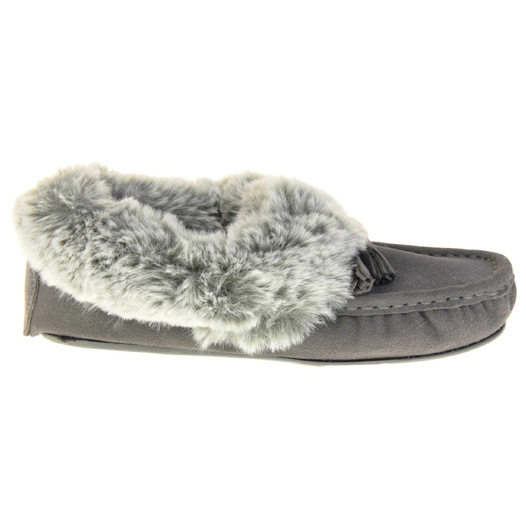 Grey Moccasin Slippers. Womens grey faux suede moccasin style slippers. With stitched detailing and tassels with subtle glitter on. Pale grey faux fur collar and lining. Grey firm sole. Right foot from a side profile.