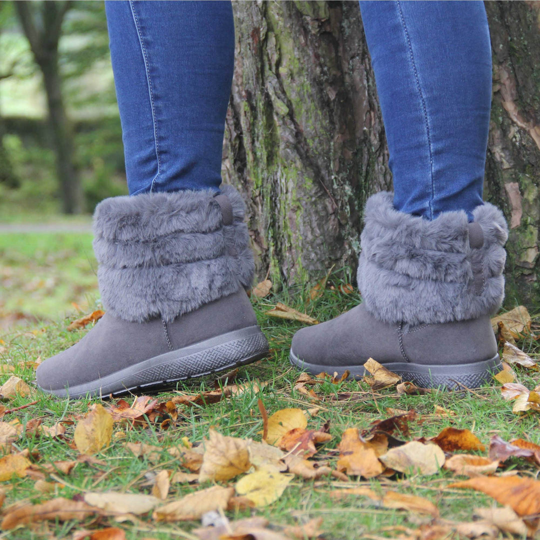 Womens Faux Fur Lined Winter Boots - Grey with suede effect upper, thick colour matching sole, plush faux fur collar. Model shot in Autumn setting with tree behind.