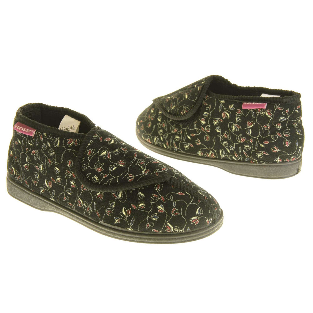 Hard sole slippers womens. Ladies bootie style slipper with a black textile upper with vine flower embroidered design. Touch fasten tab to the top and black textile lining. Firm black sole. Both feet at an angle, facing top to tail.