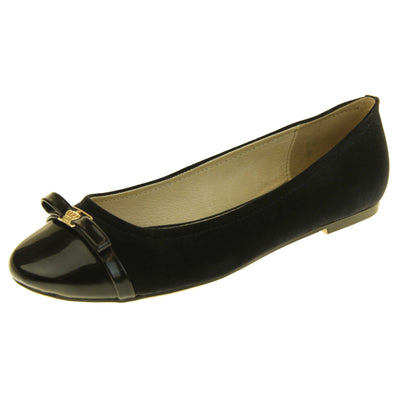 Black ballet flats. Black leather ballet pumps with black patent toe and bow detail. Black patent stripe down the heel of the upper. Beige outsole with black rim and with a very slight heel. Left foot at an angle.