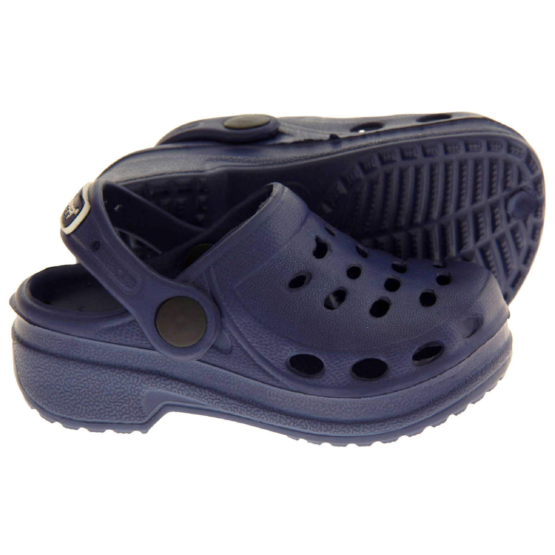 Kids Pool Shoes. Navy Blue synthetic clog style shoes. Cut out holes around the toes and the upper. Navy strap that goes along the back of your heel. The strap can be moved along the top of the shoe instead to make the shoe a mule. Both feet from side profile with left foot on its side to show the sole.