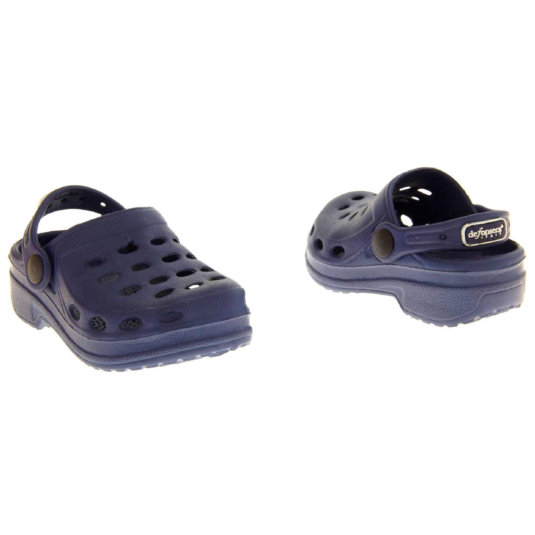 Kids Pool Shoes. Navy Blue synthetic clog style shoes. Cut out holes around the toes and the upper. Navy strap that goes along the back of your heel. The strap can be moved along the top of the shoe instead to make the shoe a mule. Both shoes at a slight angle facing top to tail.
