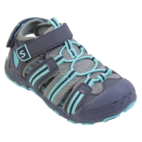 Kids beach sandals. Strappy beach sandals with grey mesh and navy faux leather uppers. with turquoise and navy textile strap detailing. Turquoise elasticated faux laces to the front. Navy faux leather straps around the front and back of the ankle with touch fastening. Turquoise insole. Navy rubbery outsole and toe bumper with turquoise and navy grip on the bottom. Right foot at an angle.