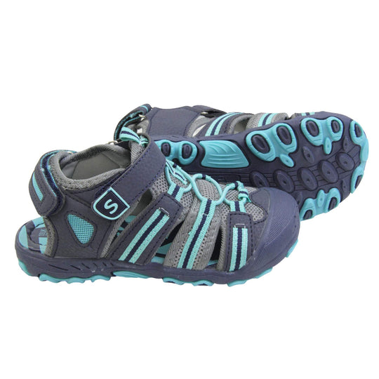 Kids beach sandals. Strappy beach sandals with grey mesh and navy faux leather uppers. with turquoise and navy textile strap detailing. Turquoise elasticated faux laces to the front. Navy faux leather straps around the front and back of the ankle with touch fastening. Turquoise insole. Navy rubbery outsole and toe bumper with turquoise and navy grip on the bottom. Both feet from a side profile with the left foot on its side behind the the right foot to show the sole.