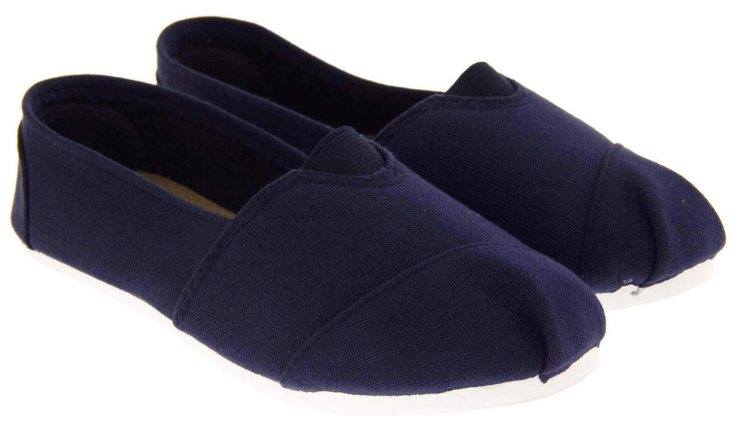 Kids canvas shoes. Navy blue canvas upper with elasticated panel in the middle where the tongue would be. White synthetic sole. Navy textile lining and insole. Both feet together from an angle.