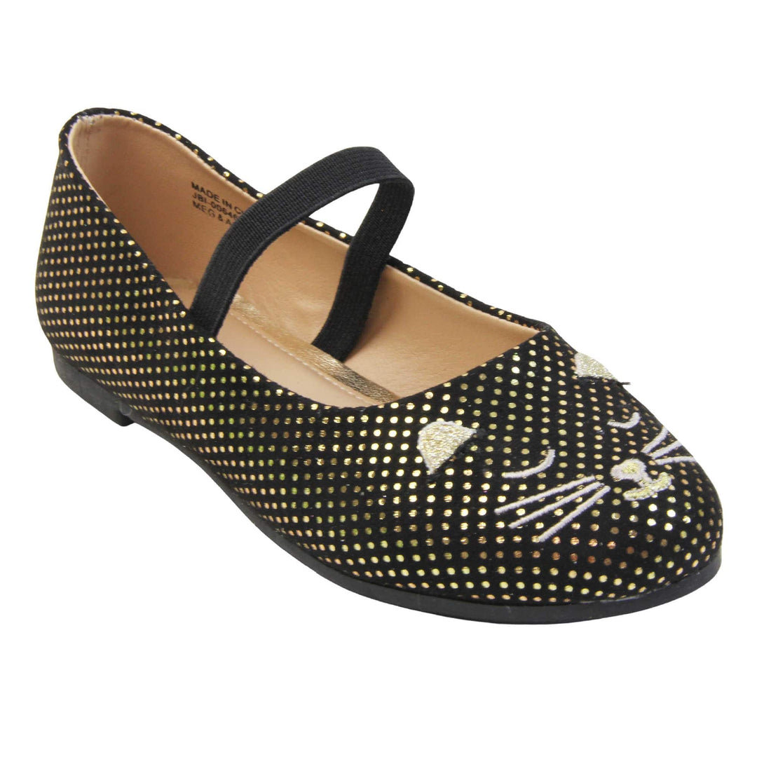 Kids cat shoes. Ballerina style shoes with black faux suede uppers with metallic gold dotty print and embroidered cat face to the front. With a black elasticated over the foot strap. Beige lining and dark brown sole with very slight heel. Right foot at an angle.