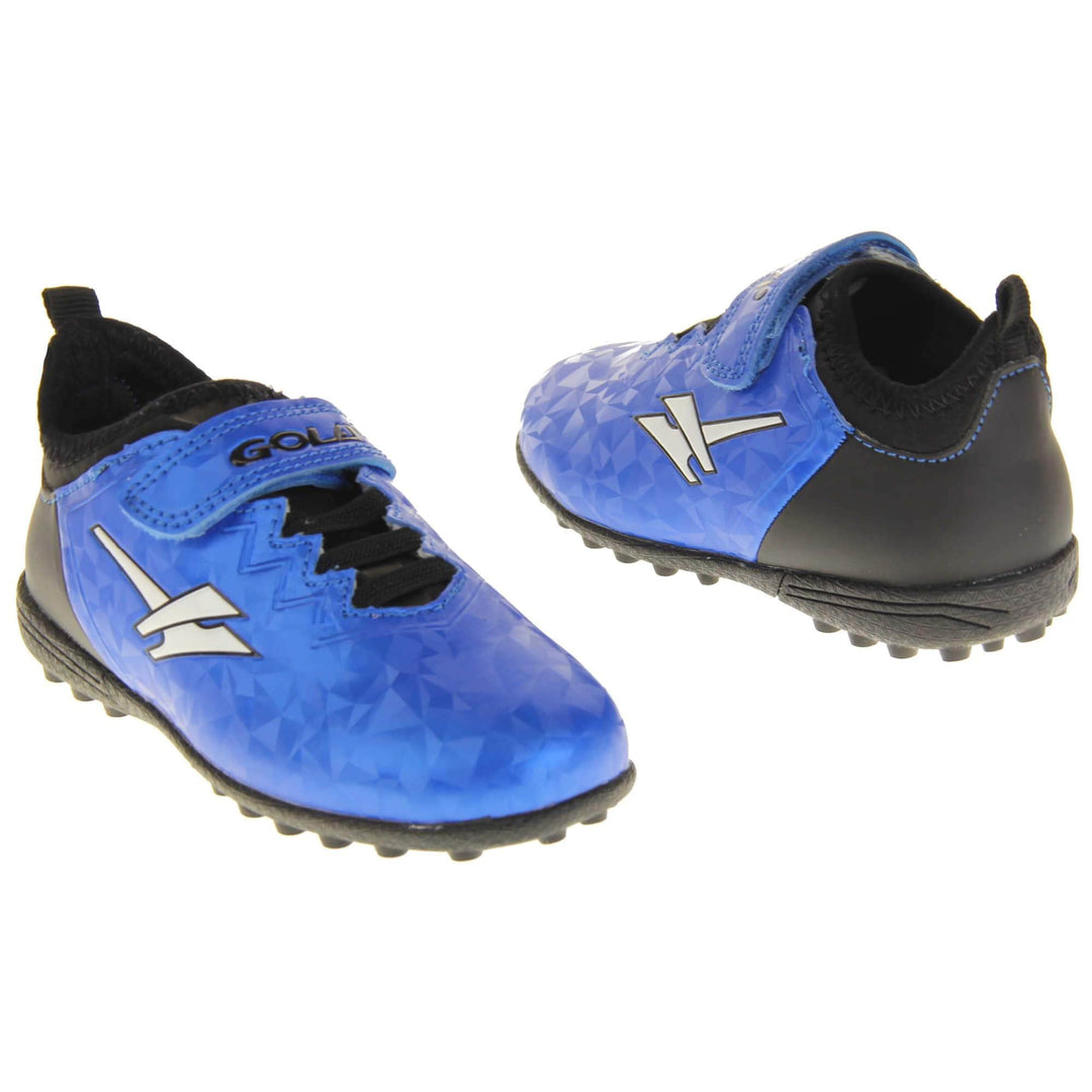 Kids football trainers. Metallic cerulean blue Gola boots with white Gola logo to the sides. With black heel and tongue and black elastic lace detail to the front. Metallic blue touch close strap with Gola branding across it. Black soles with small Astroturf studs. Both feet facing top to tail from an angle.